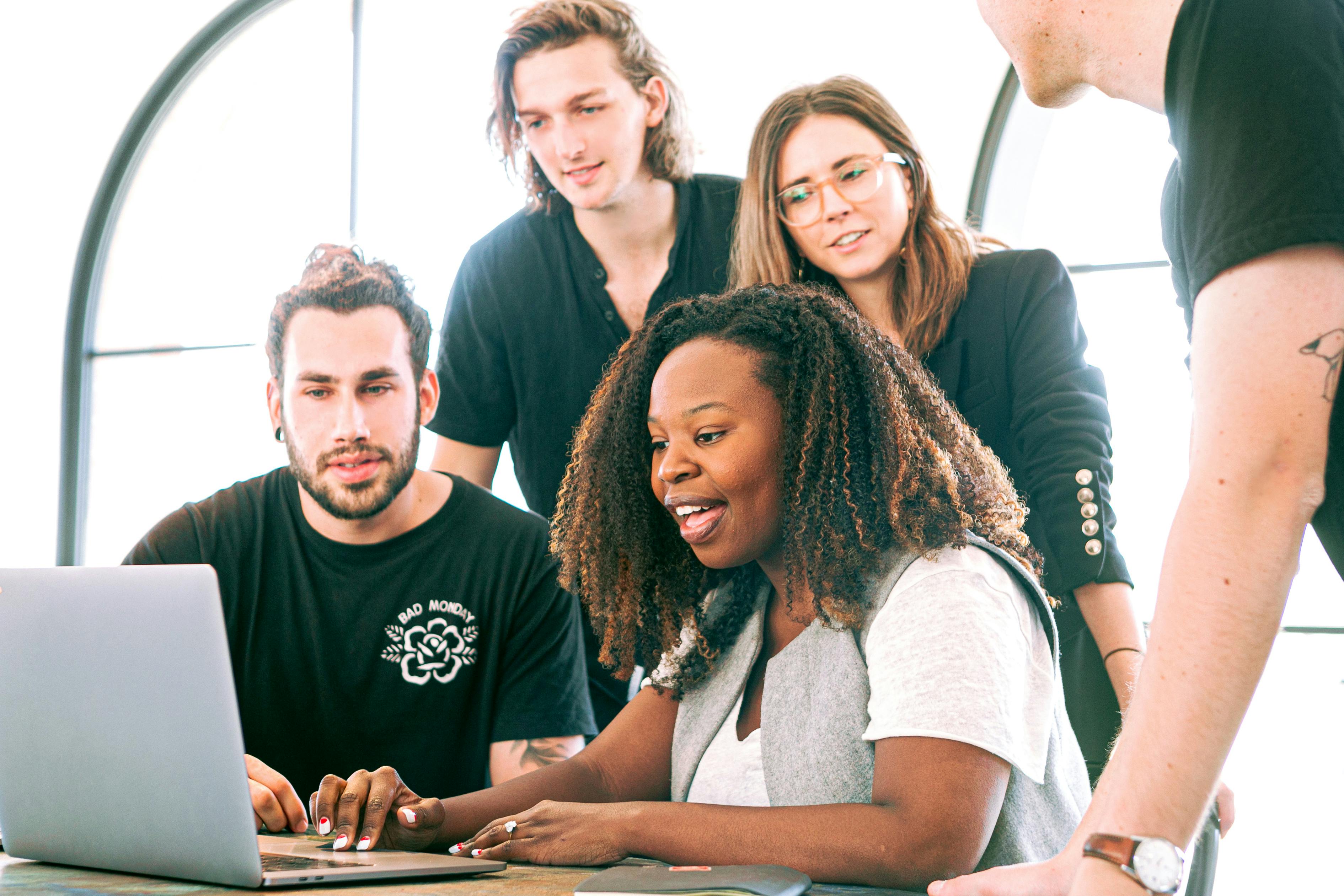 Team of 4 people looking at a laptop.