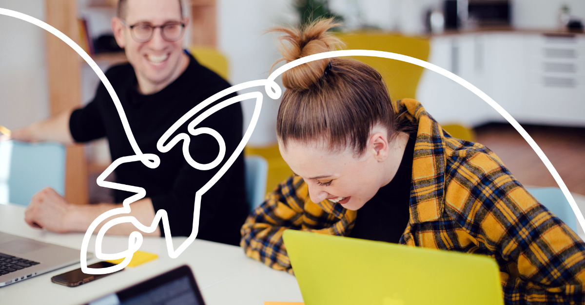 Woman and man laughing next to laptop