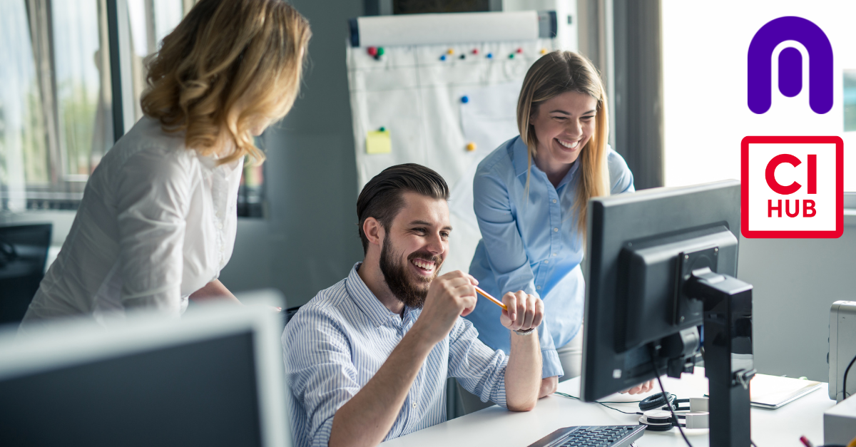 Man and 2 women in an office looking at a desk smiling