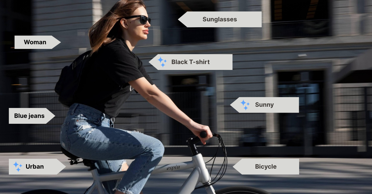 A young brunette woman rides her bike through San Francisco. The setting is urban. She's wearing a black t-shirt, sunglasses, backpack, blue jeans, and black trainers. The sun is on her face.